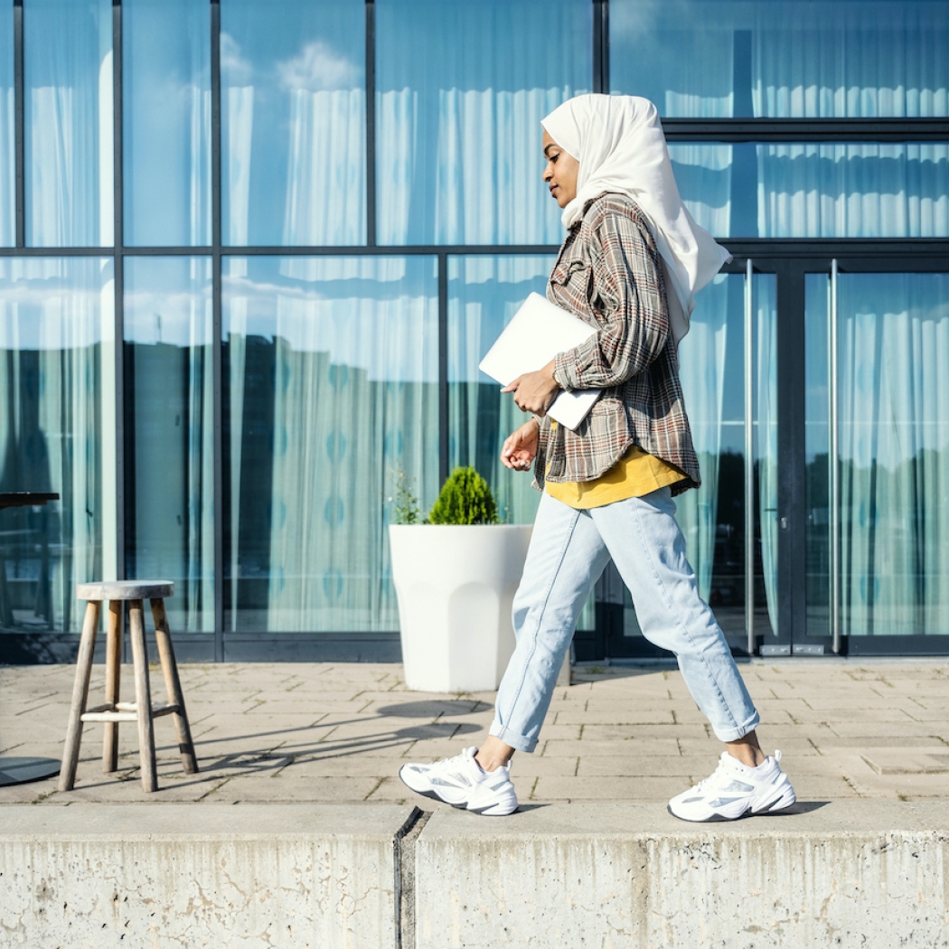 Image of woman walking with papers under arm